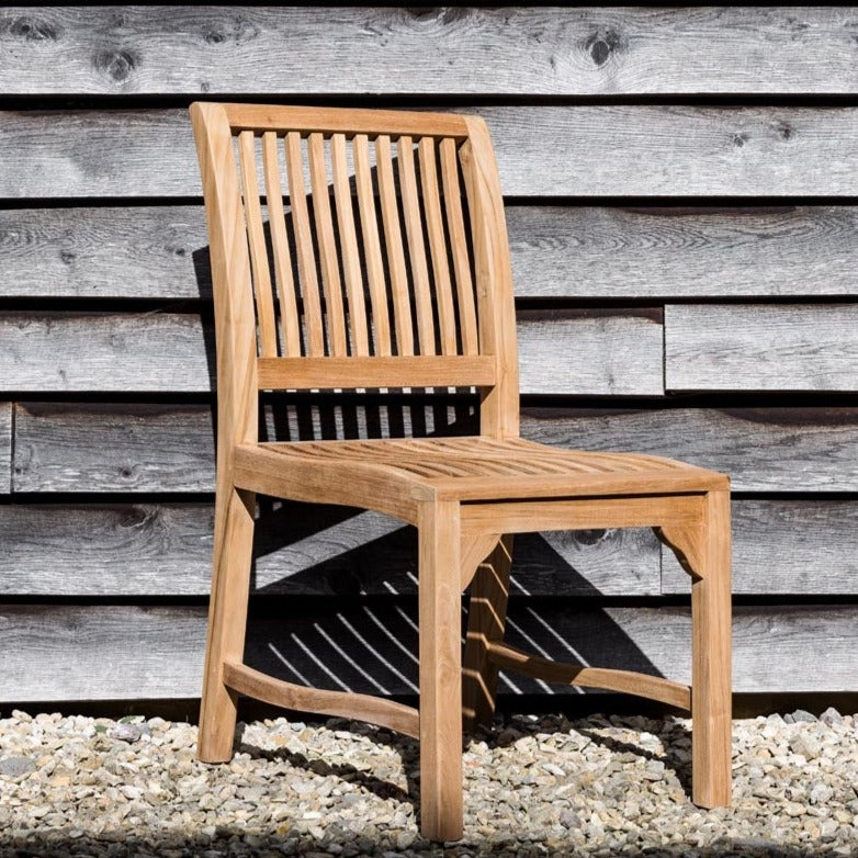  Teakunique's Bali Dining Chair on gravel against weatherboard