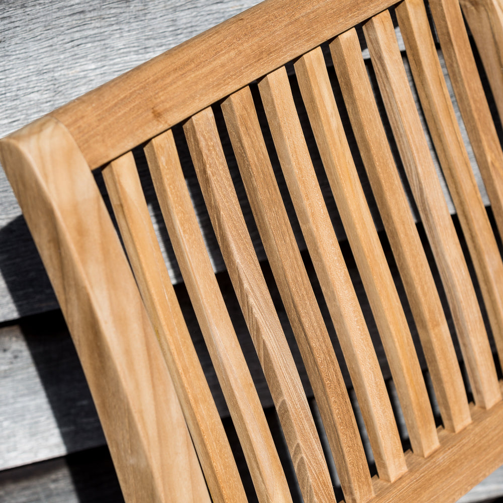 
                  
                    Close up of the backrest of a single teak outdoor dining chair.
                  
                