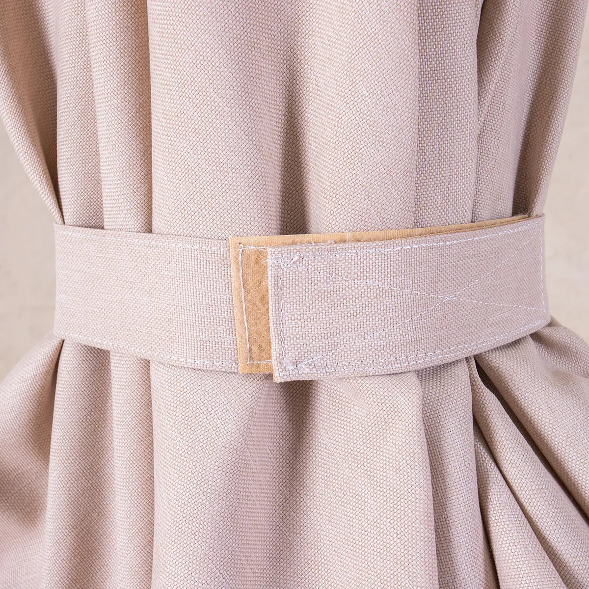 Close-up of a beige parasol canopy, held with a velcro tie  on a beige background