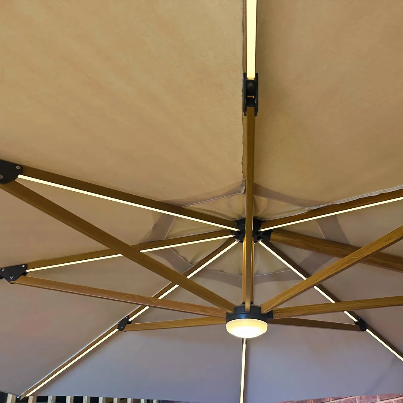 Close-up of a beige patio umbrella with wooden frame and metal hardware.