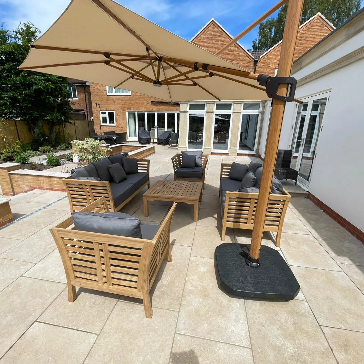Outdoor patio area with wooden furniture and large umbrella on a sunny day.