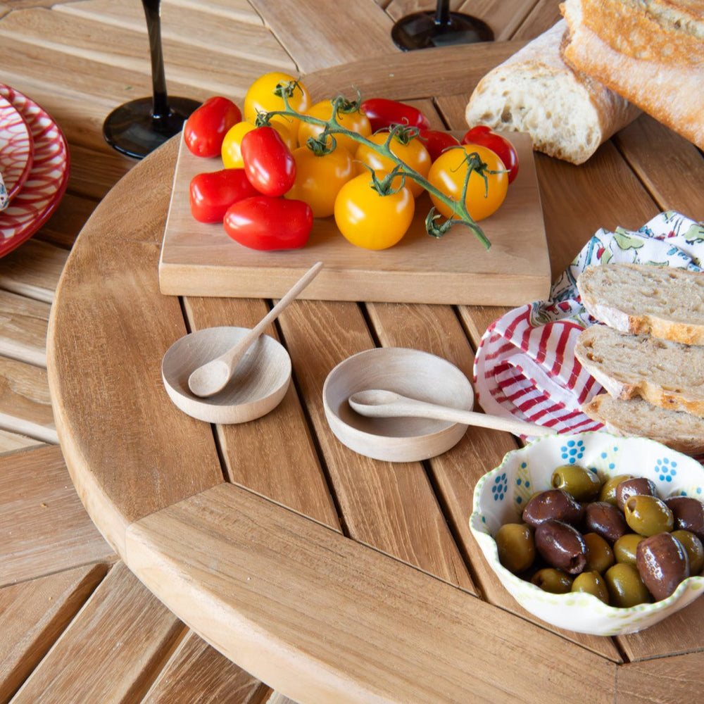 
                  
                    Round teak wood turntable with food and wooden dishes, on a teak wood table. 
                  
                