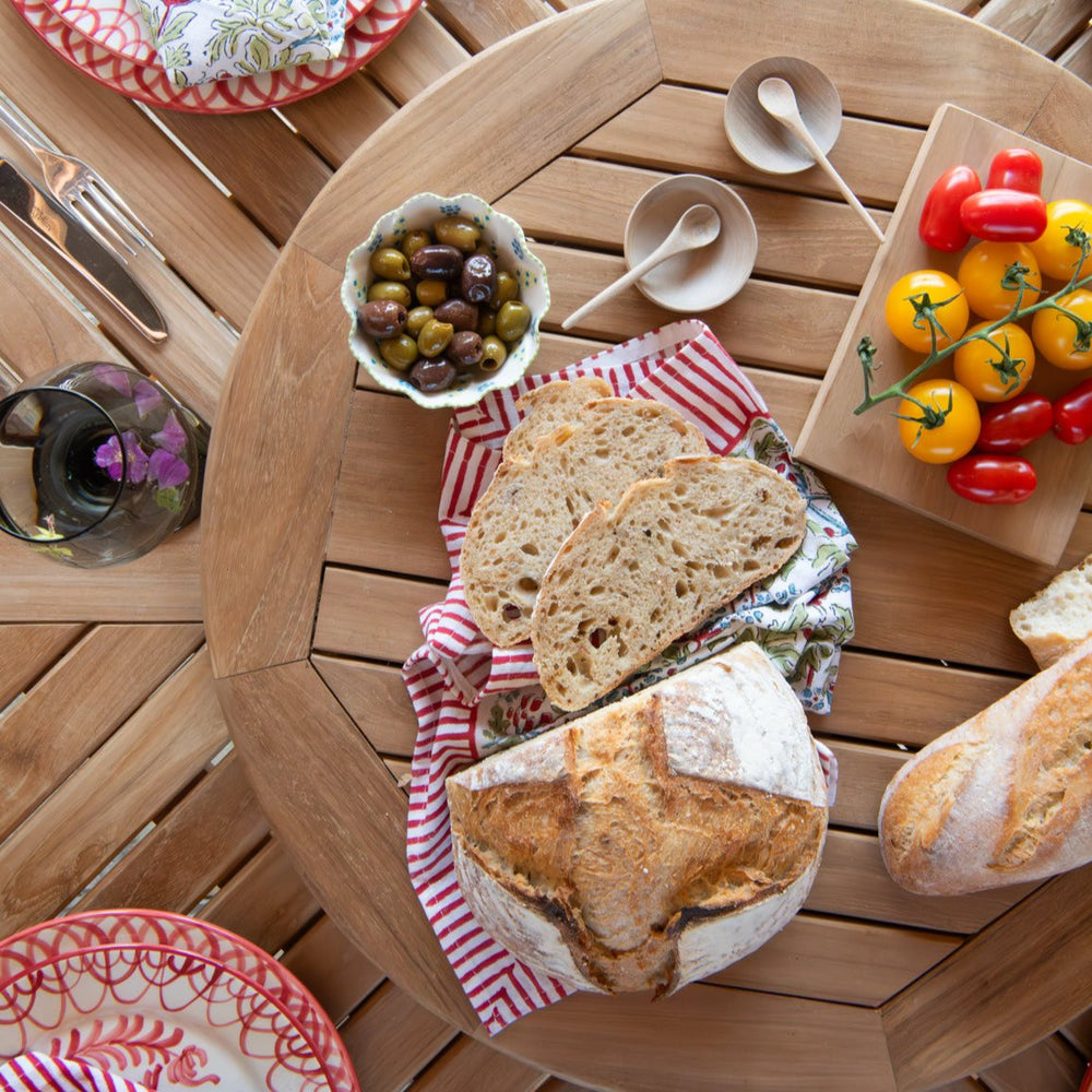 
                  
                    Overhead shot of teak round turntable with food and wooden dishes, on a teak table with glasses and place settings
                  
                