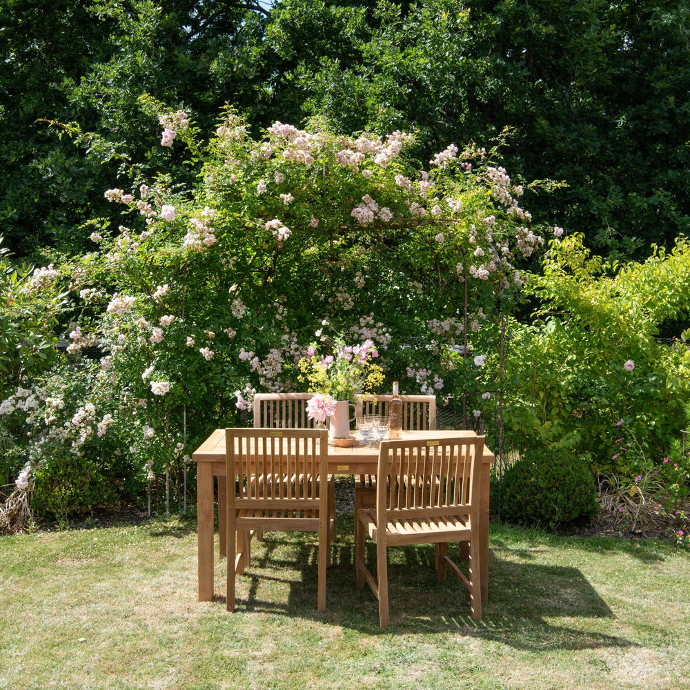 
                  
                    Teak outdoor dining set with teak rectangular table and chairs in a garden setting
                  
                
