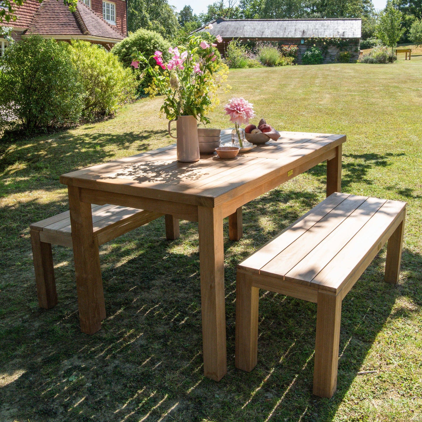 Teak outdoor dining set with rectangular table and benches, in garden setting. 