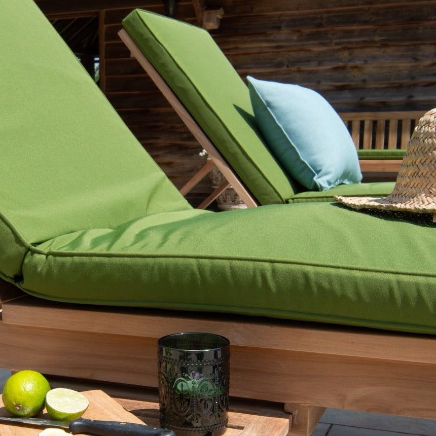 
                  
                    Two teak lounger chairs side by side, with bright green seat and back cushions and small teak table in foreground 
                  
                