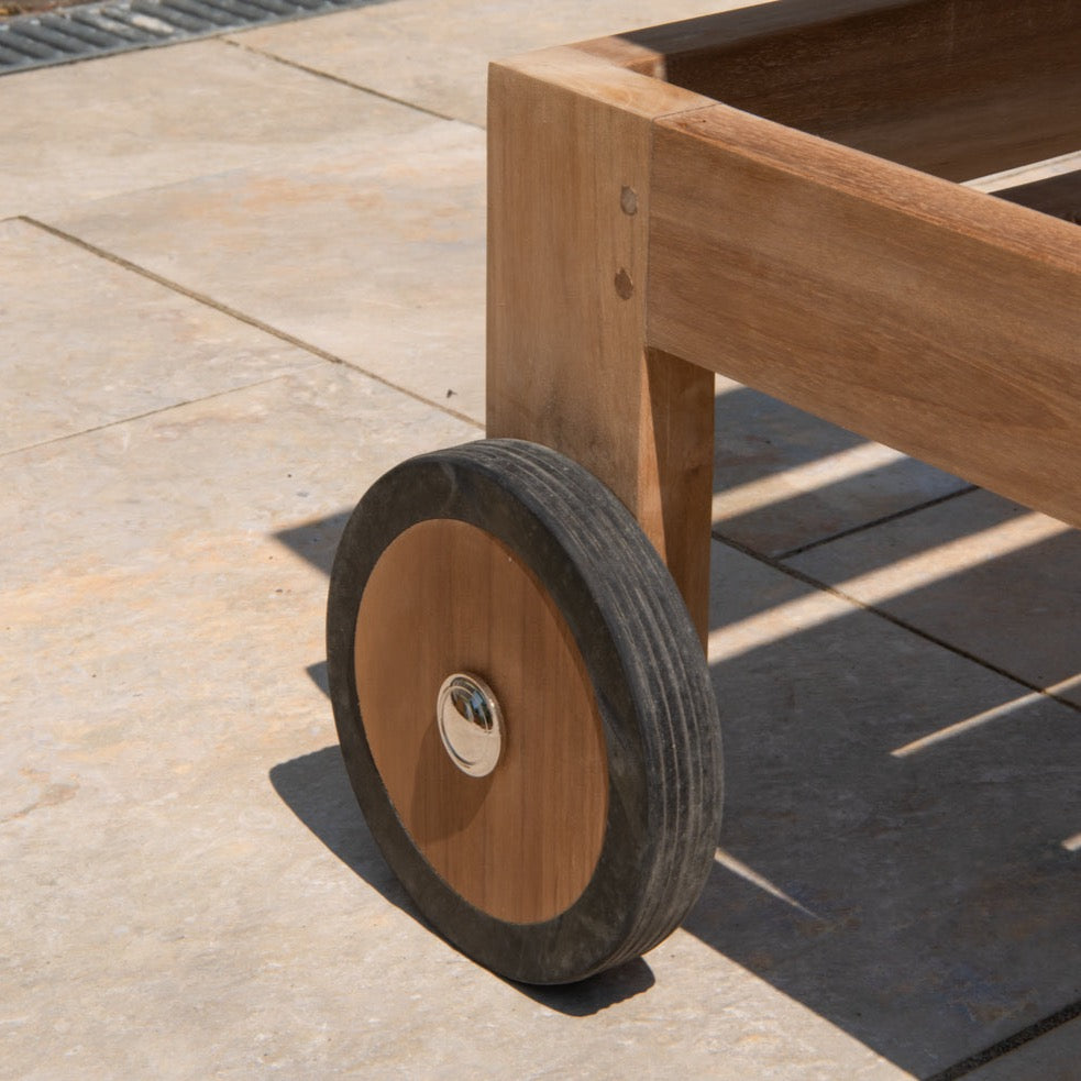 close up of wheel and corner of teak reclining chair, on stone patio