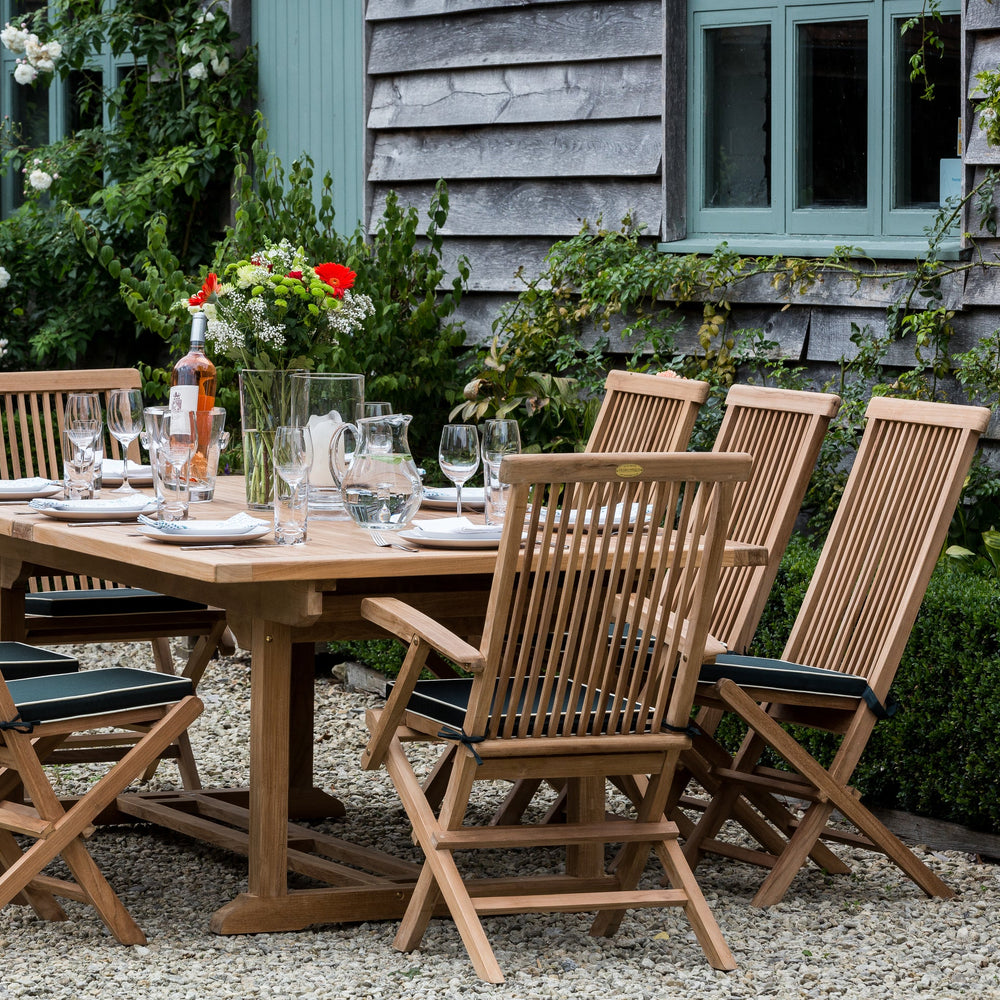 Teak outdoor dining set with chairs and table in a garden setting.