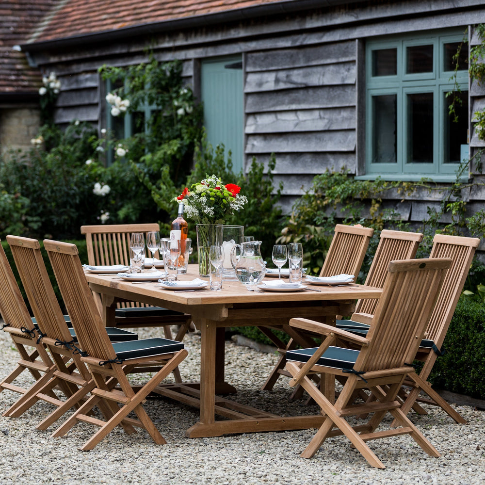 Teak outdoor dining set with chairs and table in a garden setting.