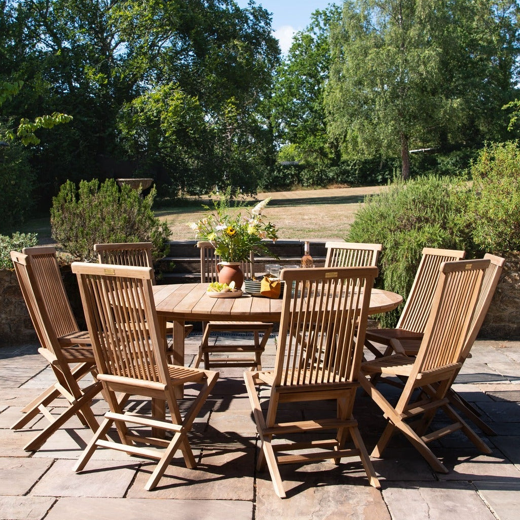 Teak wooden outdoor dining set on a patio with garden view