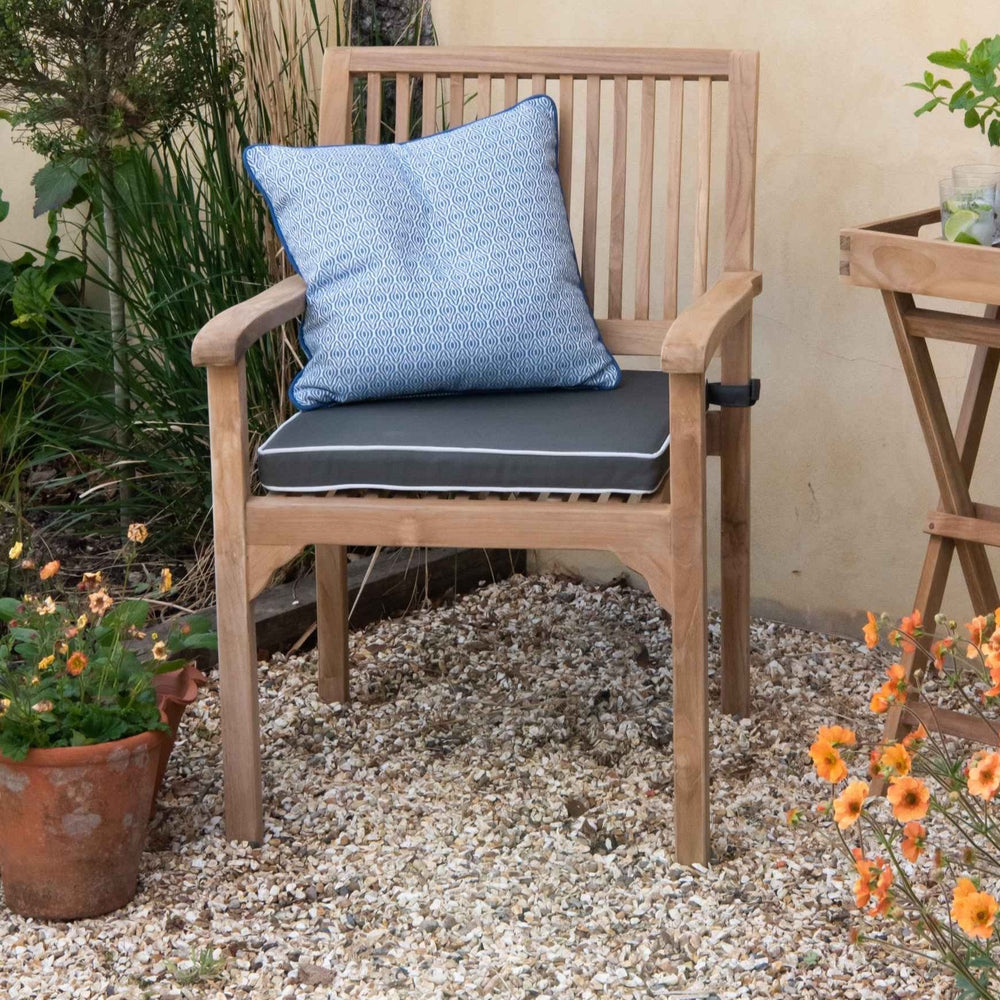 Teak Bali Carver Chair with dark grey and white seat cushion, and blue patterned scatter cushion in an outdoor setting
