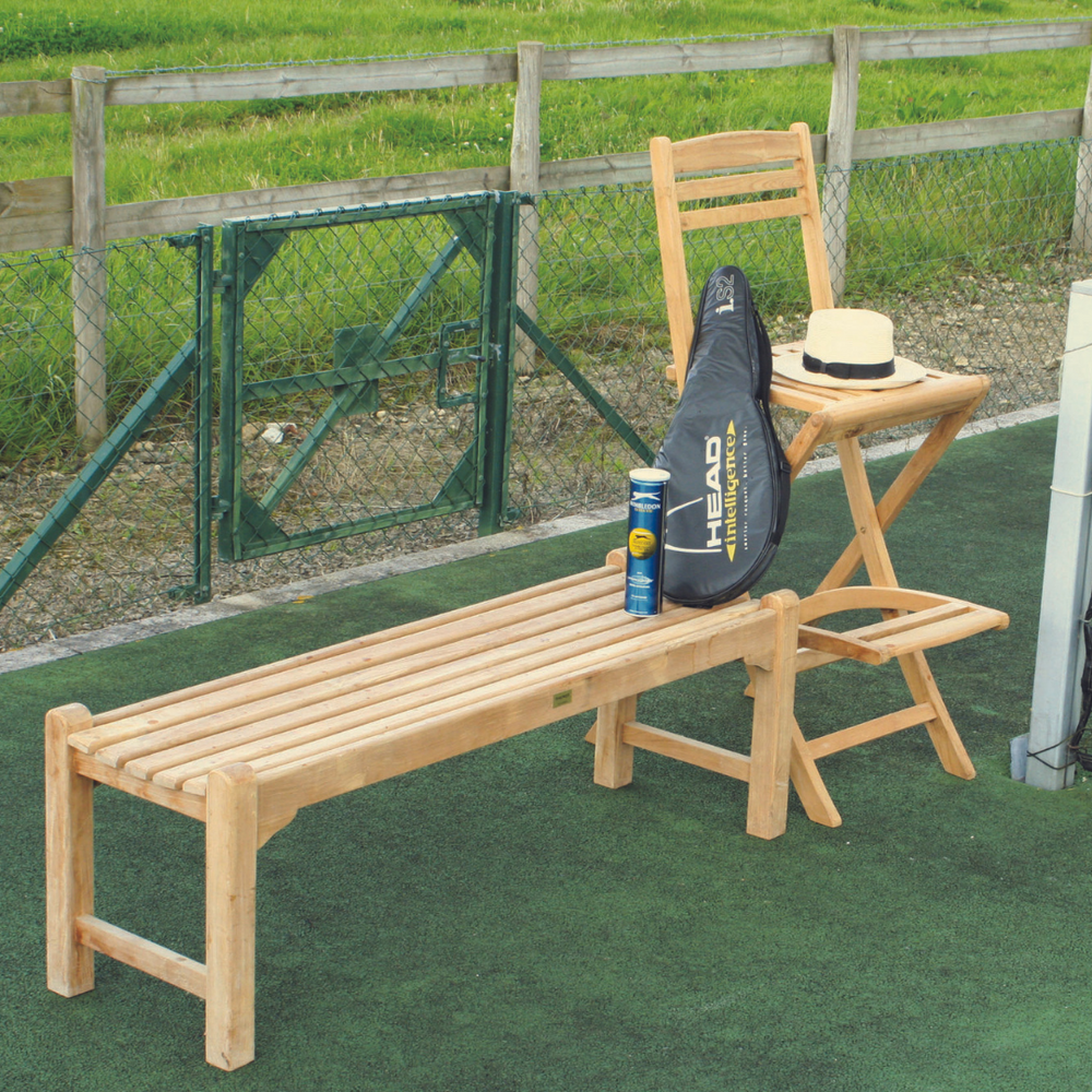 
                  
                    Single teak bench next to teak high umpire chair, on tennis court with tennis racket and balls.  
                  
                
