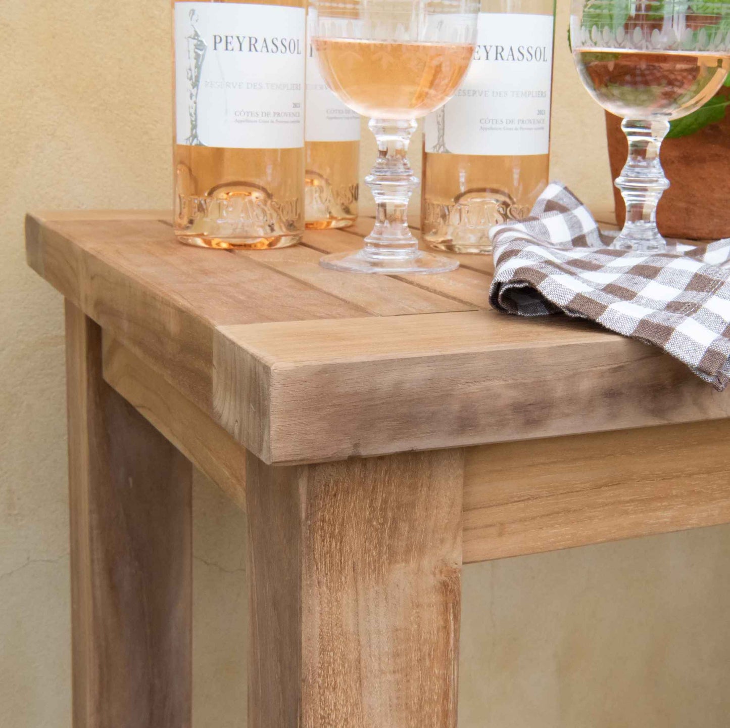 Corner of teak rectangular side table with wine glasses and wine botles 