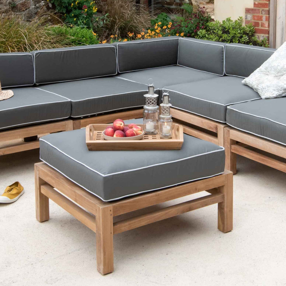 
                  
                    Teak Modular Corner Outdoor Sofa with green - grey seat and back cushions. In front is teak ottoman with same coloured cushion and tray of candles and fruit.  
                  
                
